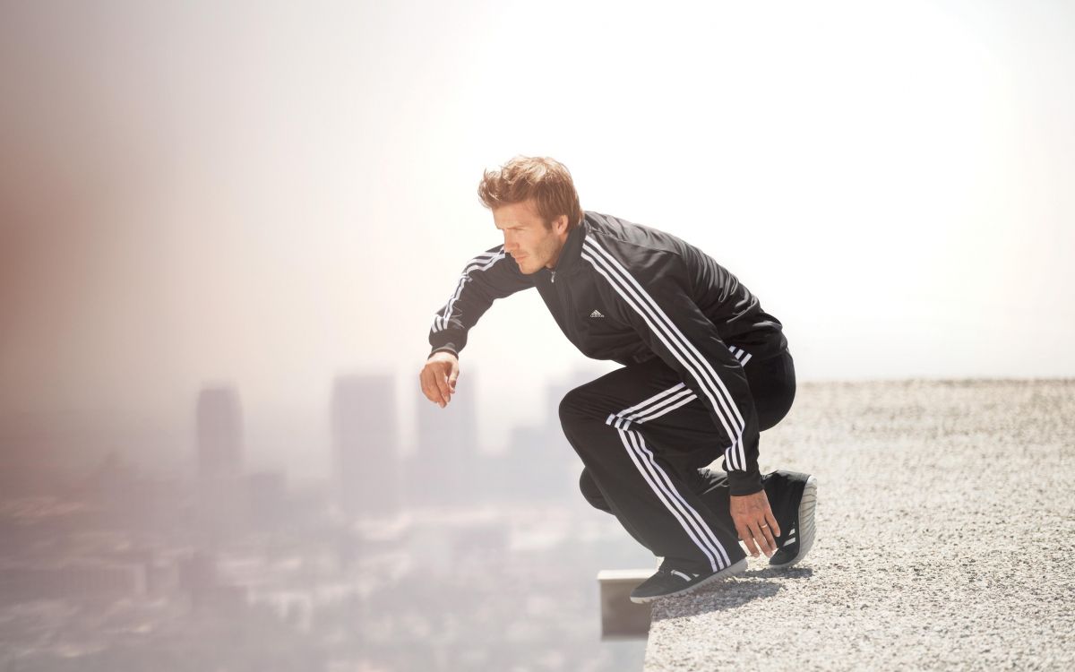 man in black leather jacket and black pants sitting on white concrete bench during daytime