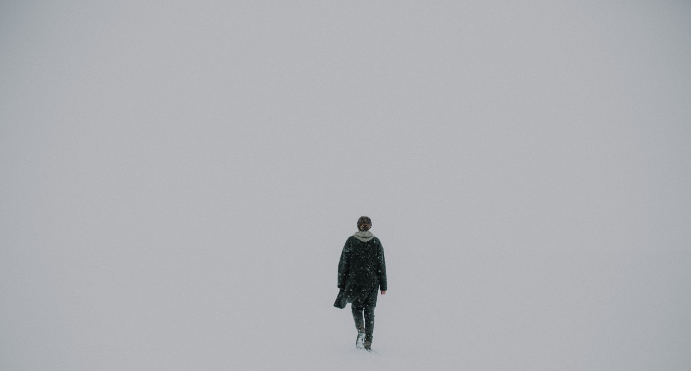 man in black jacket standing on snow covered ground