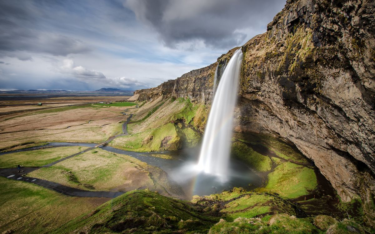 waterfalls on green grass field under gray cloudy sky during daytime