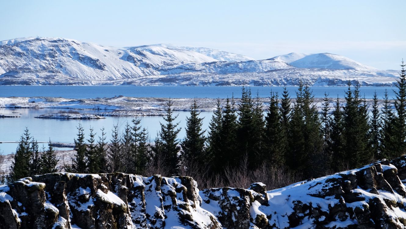 snow covered mountain near body of water during daytime