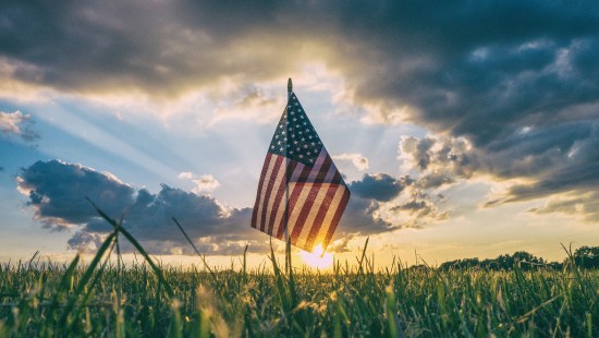 Image us a flag on green grass field under cloudy sky during daytime