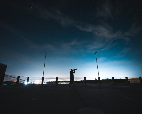 Image silhouette of person standing on sidewalk during night time