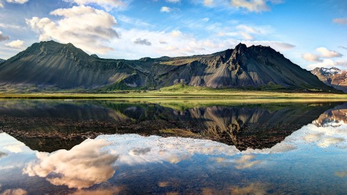 Image green and brown mountains beside lake under blue sky during daytime