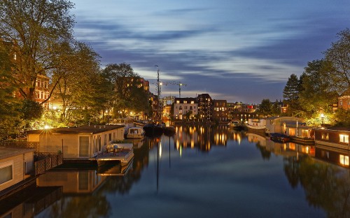 Image body of water near green trees and buildings during daytime