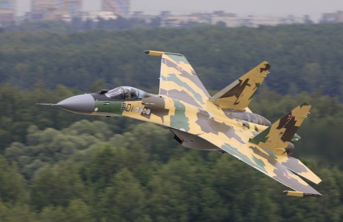 Image green and yellow fighter jet flying over green trees during daytime