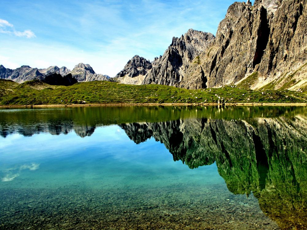 lake near mountain under blue sky during daytime