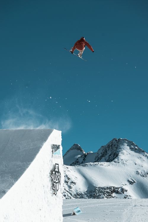 person in red jacket and black pants on snow covered mountain during daytime