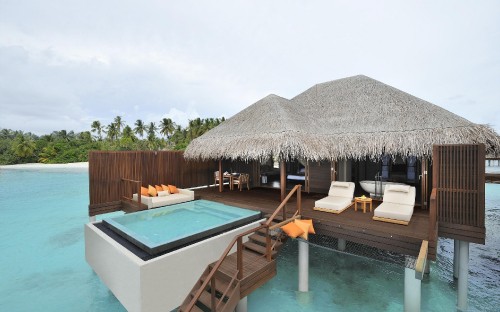 Image brown wooden beach house near swimming pool under blue sky during daytime