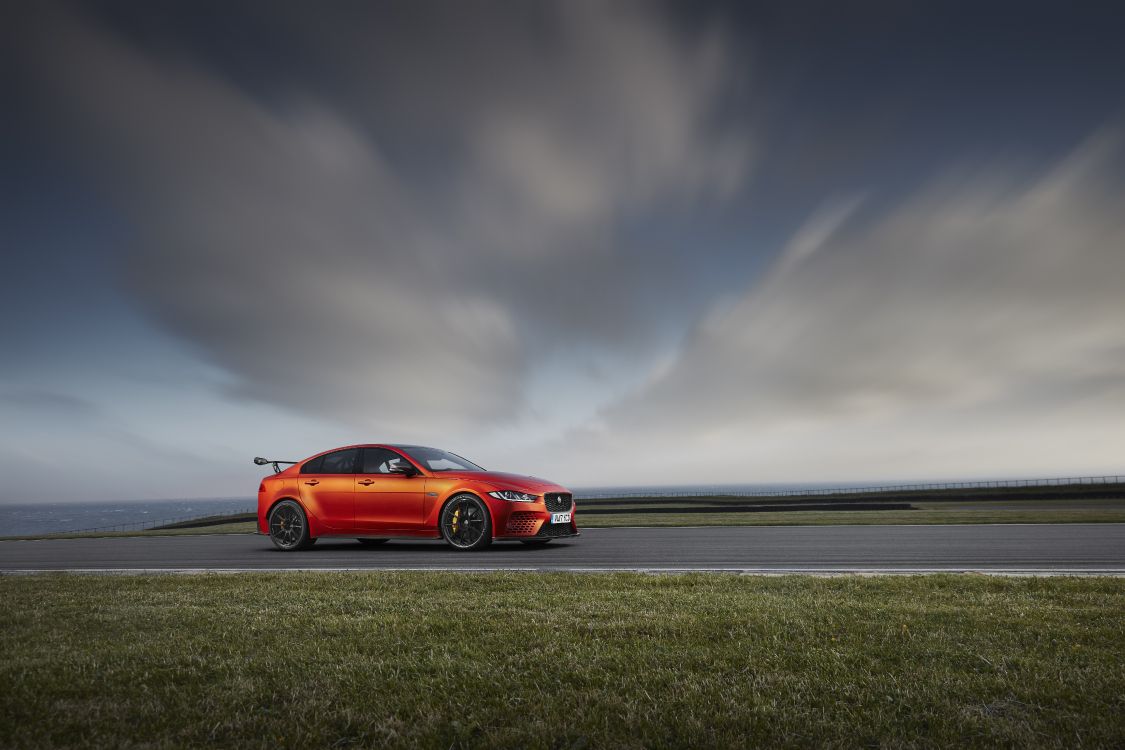 Red Coupe on Gray Asphalt Road Under Gray Cloudy Sky. Wallpaper in 8603x5735 Resolution