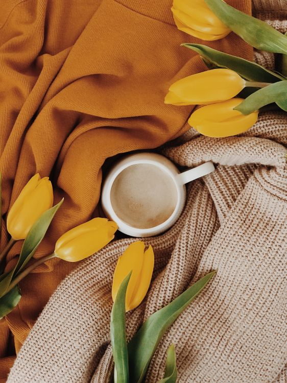 white ceramic mug on yellow textile