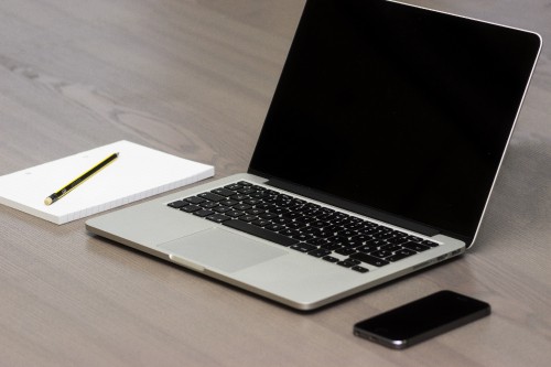 Image macbook pro beside black smartphone on brown wooden table