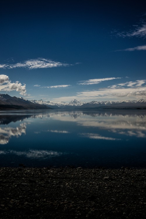 Image body of water near mountain under blue sky during daytime