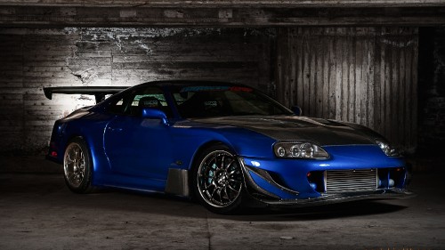 Image blue porsche 911 parked beside gray wall