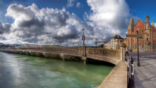 Image brown concrete bridge over river under blue sky and white clouds during daytime