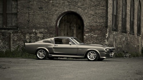 Image grayscale photo of coupe parked beside brick wall