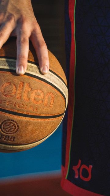 Image person holding red and black basketball