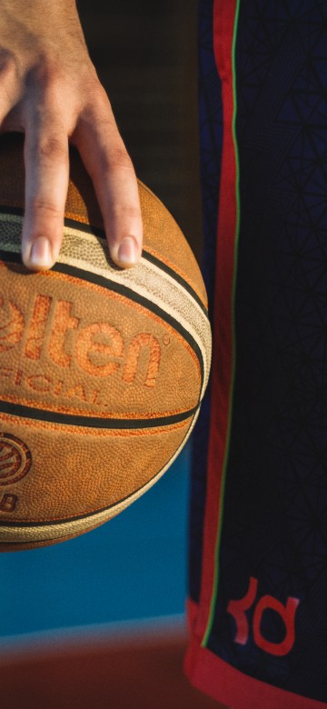 Image person holding red and black basketball