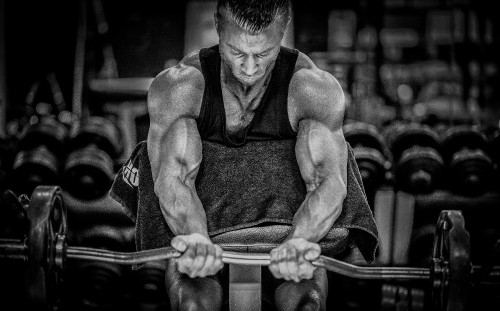 Image topless man in black shorts sitting on gray metal bar