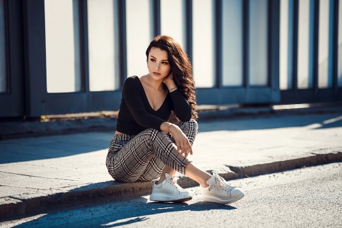 Image woman in black long sleeve shirt and black and white striped skirt sitting on concrete floor