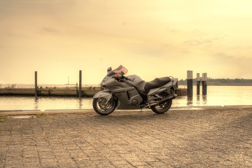 Image black motorcycle parked on gray concrete pavement during daytime