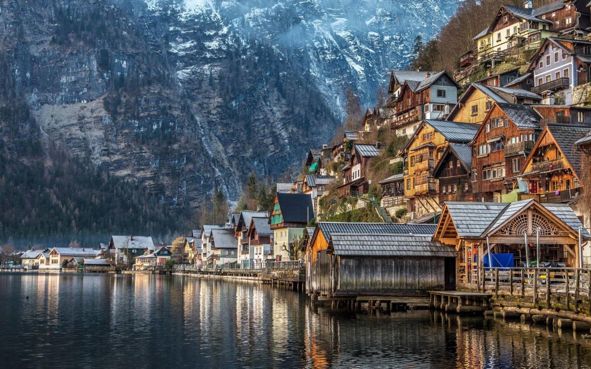 houses near body of water and mountain during daytime