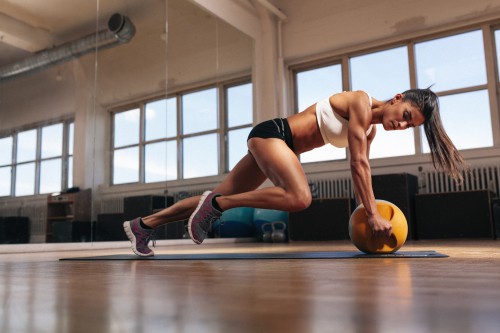 Image woman in black sports bra and black shorts doing push up