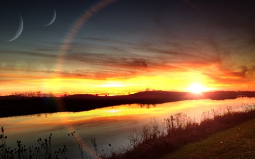 Image green grass field near body of water during sunset