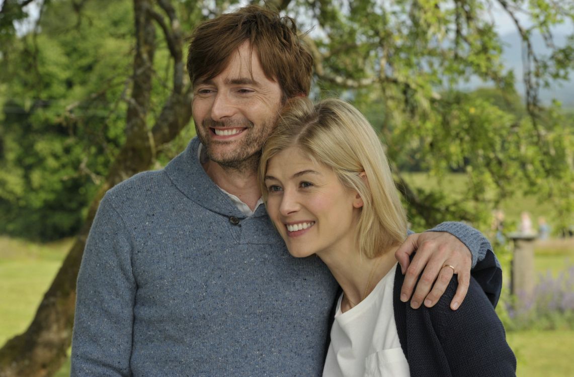 man in gray sweater smiling beside woman in white dress