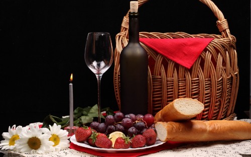 Image strawberries and grapes on brown woven basket beside wine glass