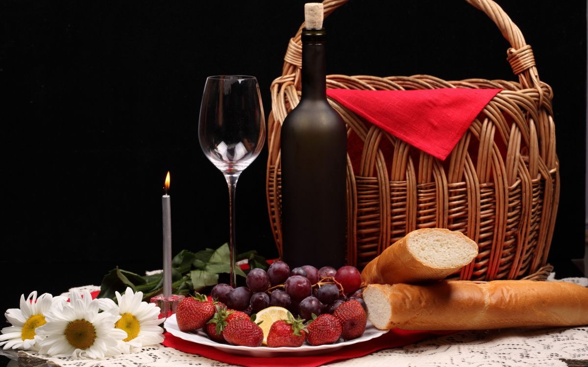 strawberries and grapes on brown woven basket beside wine glass