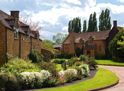 Image brown brick building near green grass field under white clouds during daytime