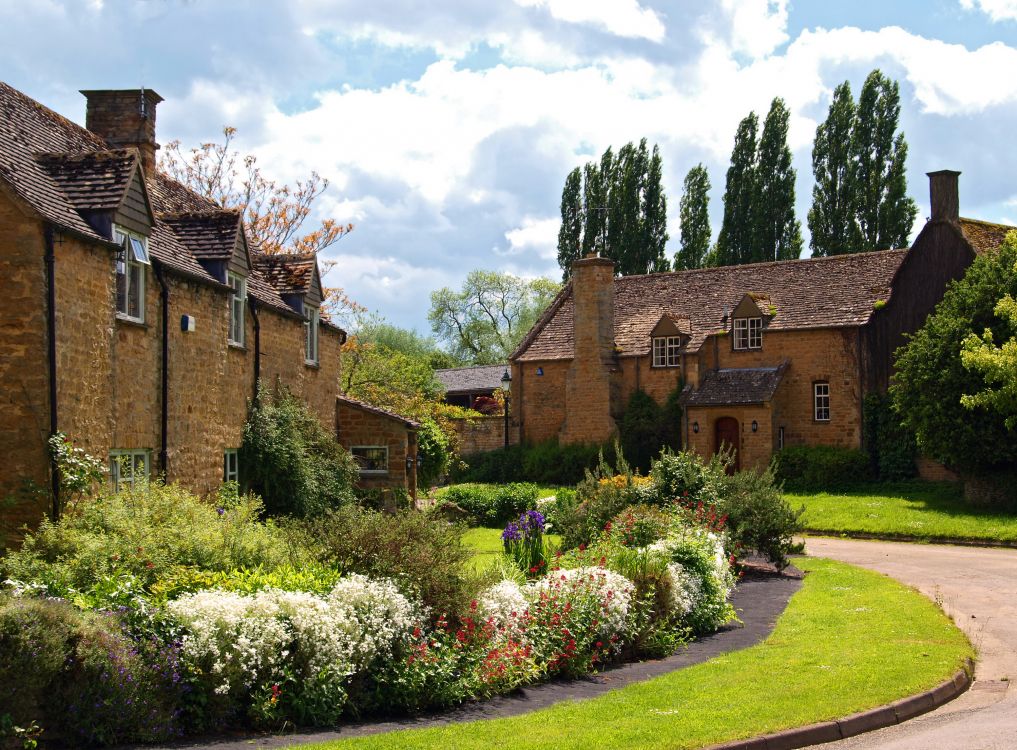 brown brick building near green grass field under white clouds during daytime