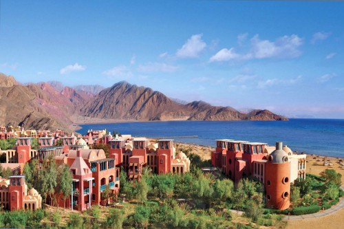 Image brown and white concrete houses near body of water under blue sky during daytime