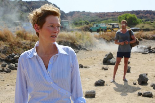 Image woman in white button up shirt standing on brown sand during daytime