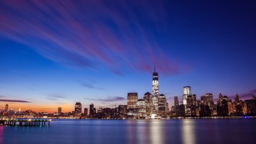 Image city skyline across body of water during night time