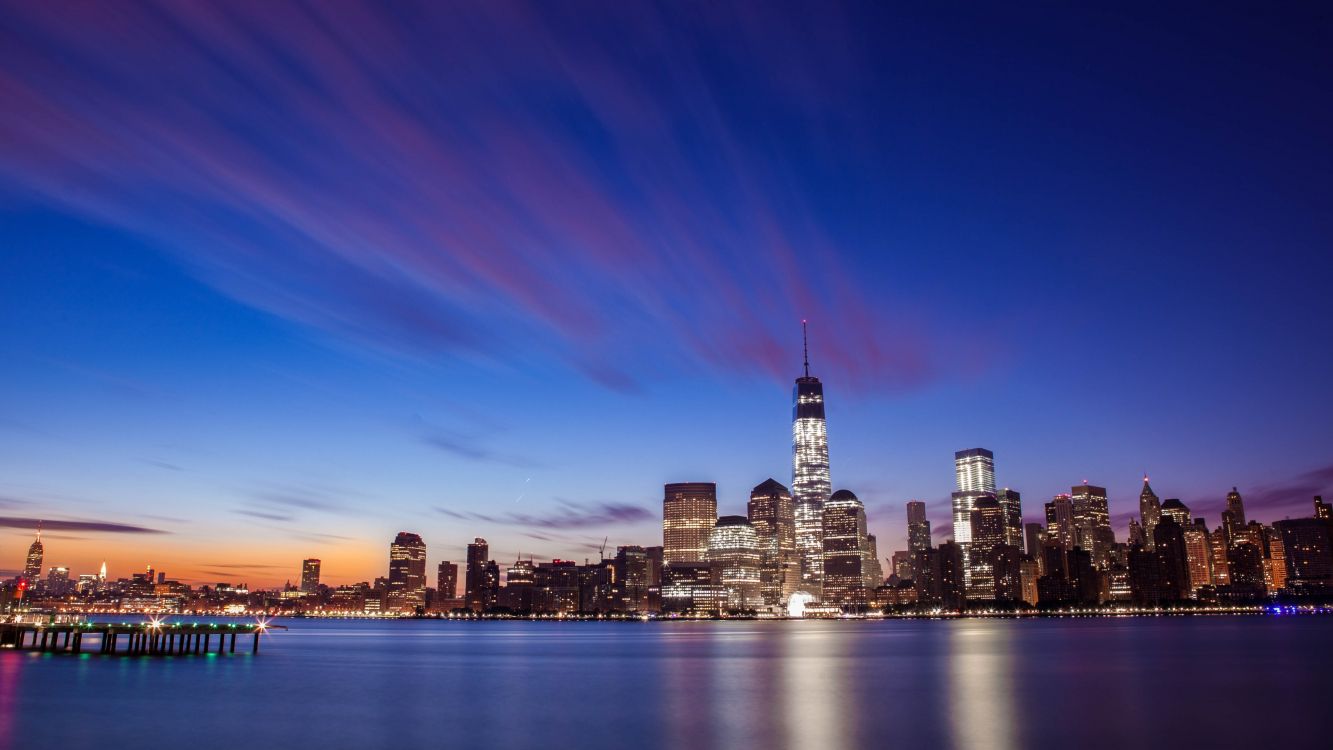 city skyline across body of water during night time