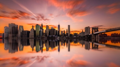 Image city skyline across body of water during sunset