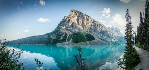 Image green and gray mountain beside body of water under blue sky during daytime