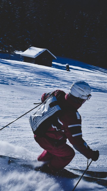 Image man in red and black jacket and black pants riding ski blades on snow covered ground