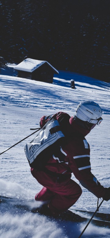 Image man in red and black jacket and black pants riding ski blades on snow covered ground