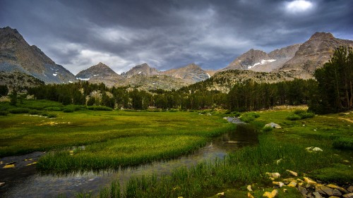 Image green grass field near mountain under cloudy sky during daytime