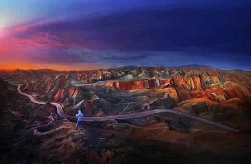 Image woman in white shirt and blue denim jeans standing on brown rock formation during daytime