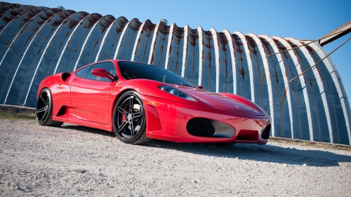 Image red ferrari 458 italia parked on gray sand during daytime