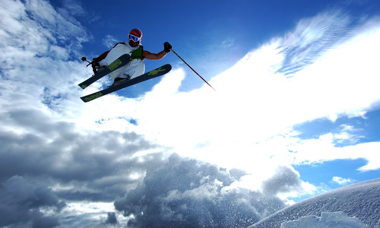 person in red jacket and white pants riding on white and red snowboard during daytime