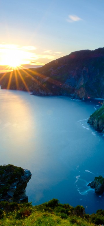 Image green and brown mountain beside body of water during daytime