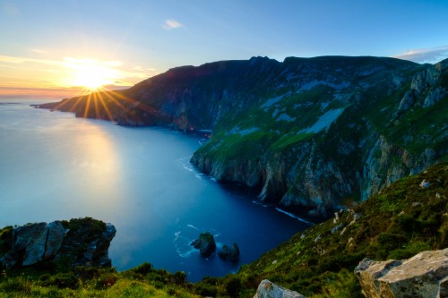 Image green and brown mountain beside body of water during daytime