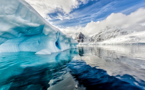 Image snow covered mountain near body of water during daytime