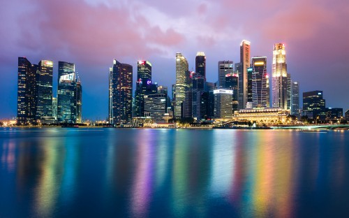 Image city skyline across body of water during night time