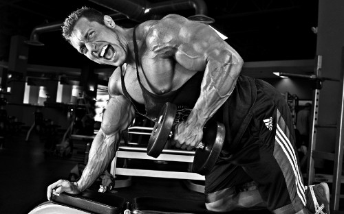 Image man in black shorts sitting on black and silver exercise equipment