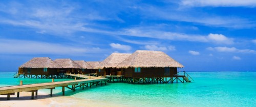 Image brown wooden beach house on blue sea under blue sky during daytime